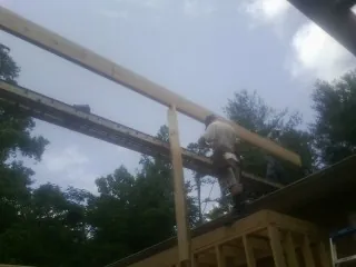 Carpenter setting a ridge beam over a new addition frame — Ice Dam Removal by Roofing Brothers in Laotto