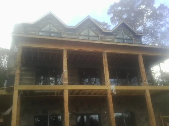 Dormers and porch framing on a large log home under construction — Roof Coating work by our crew in Laotto