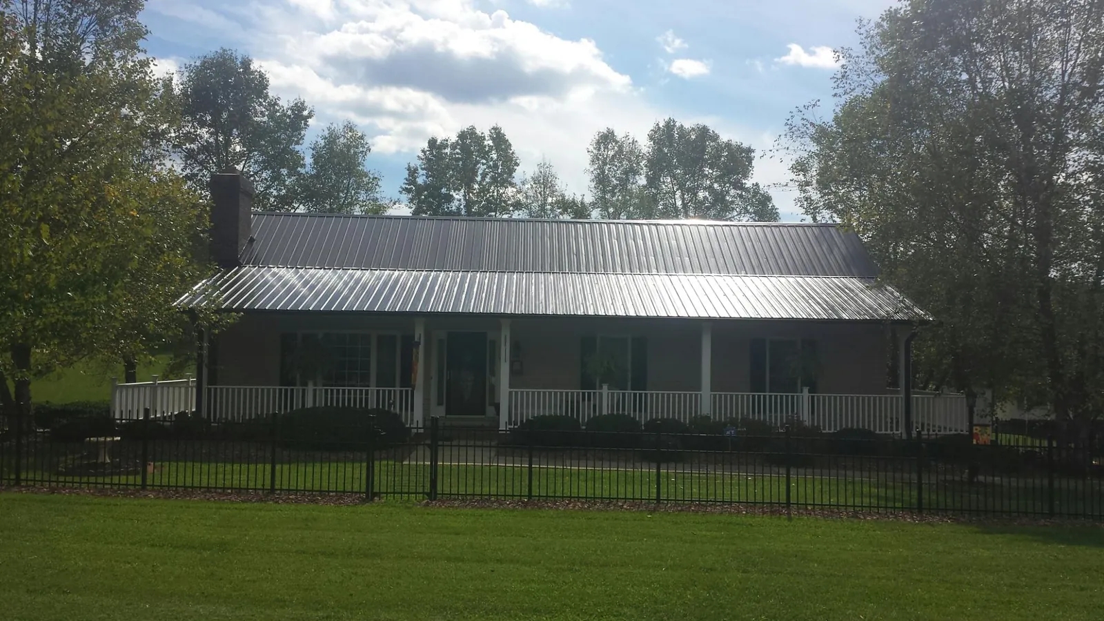 Gray metal roof on a brick ranch with a full width front porch — Gutter Guard Installation work by our crew in Laotto