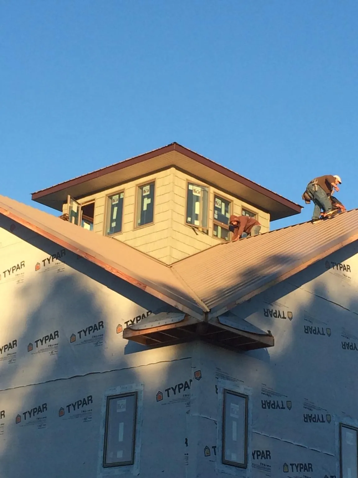 Roofers working around a rooftop cupola on a new metal roof at sunset — Roof Waterproofing in Laotto by Roofing Brothers